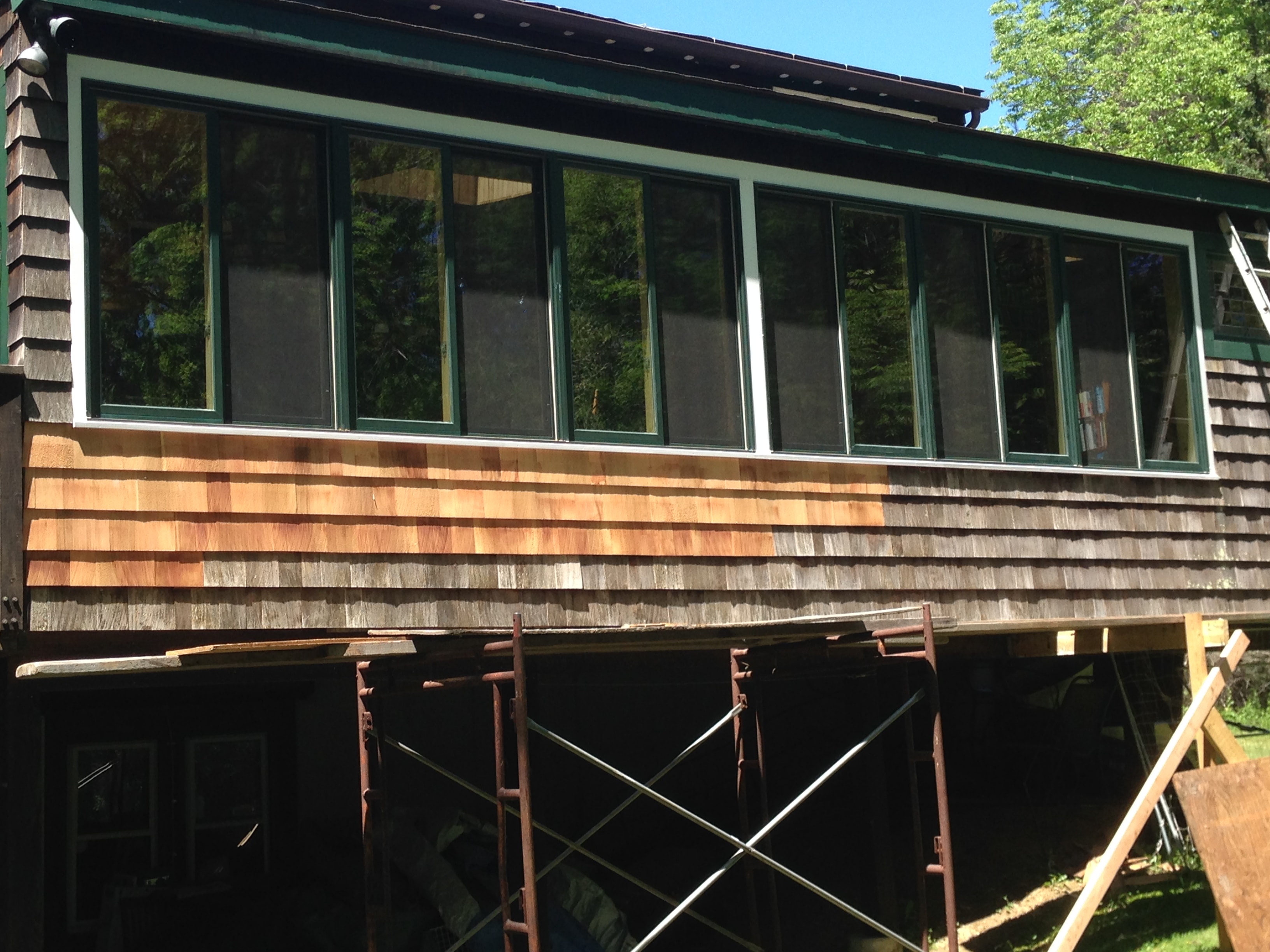Sunroom renovation — finished exterior with new cedar shingles and green-framed windows